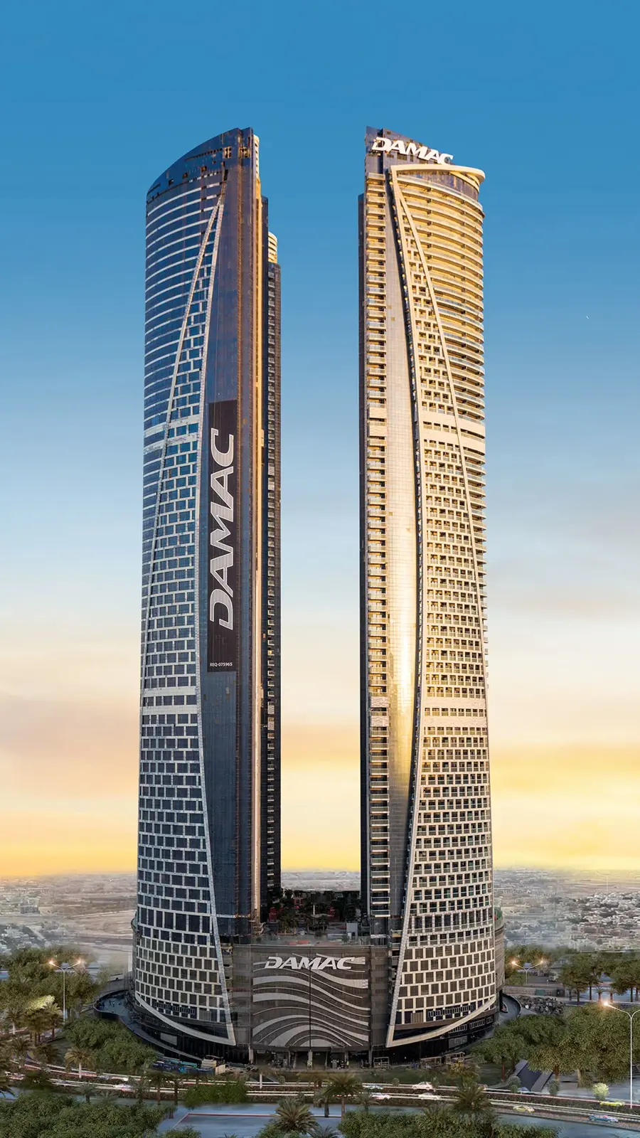 Two curved glass towers with DAMAC signage at sunset