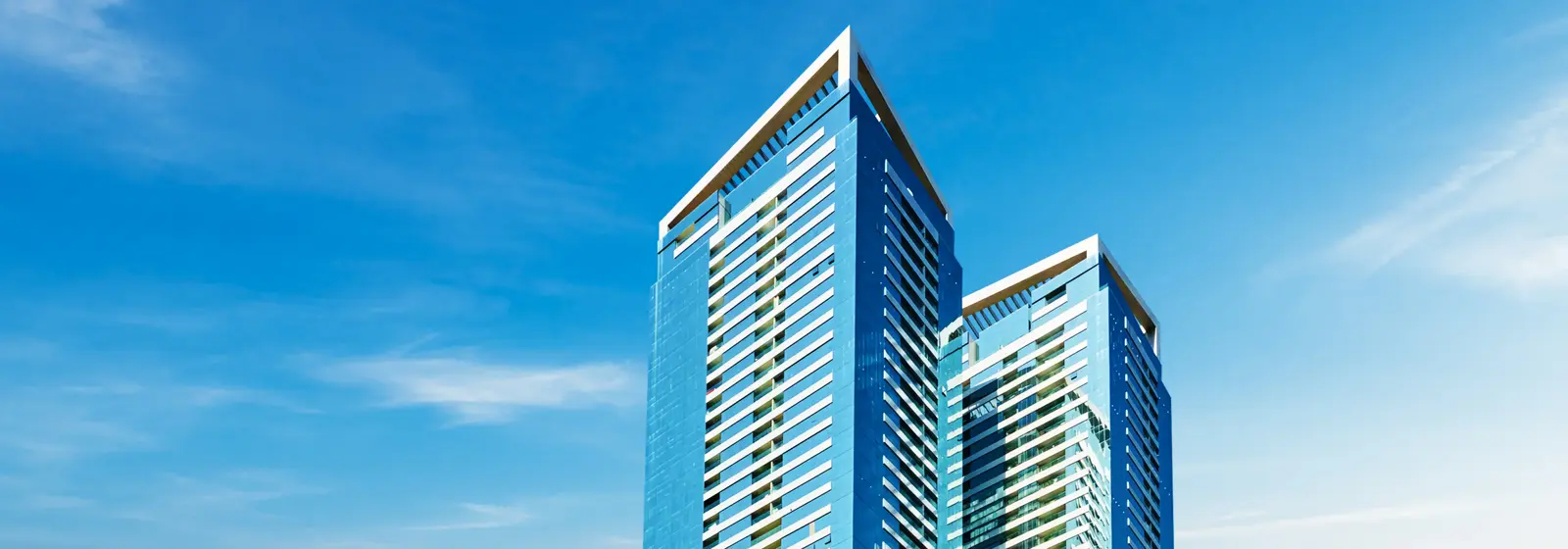 Two blue glass towers against a bright sky