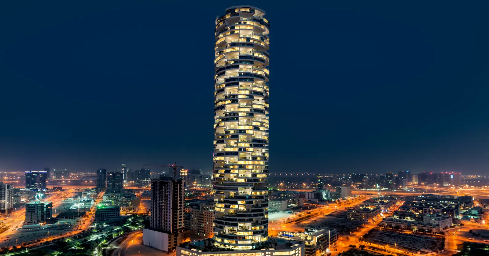 Cylindrical tower lit up at night over the city