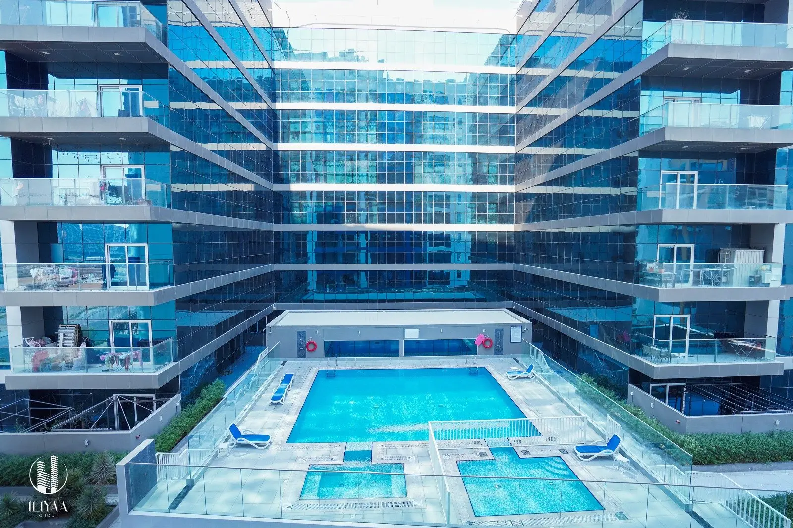 Podium pool and jacuzzi surrounded by glass-facade buildings