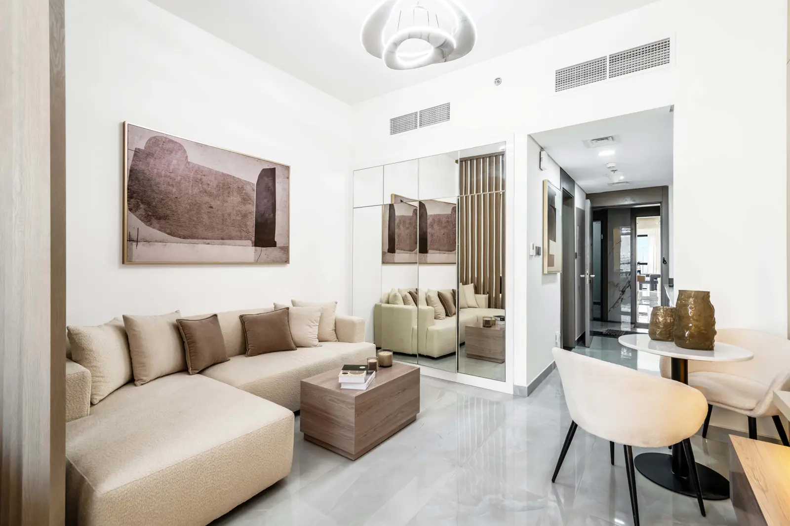 Studio living area with corner sofa and mirrored wardrobe