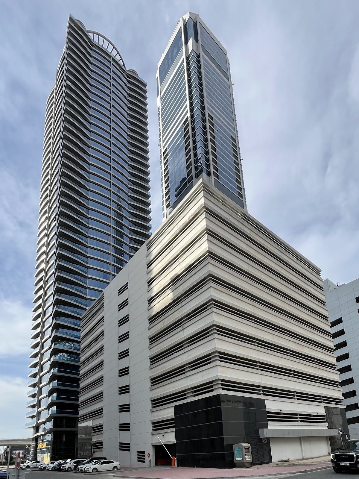 Two towers rising behind a striped parking podium