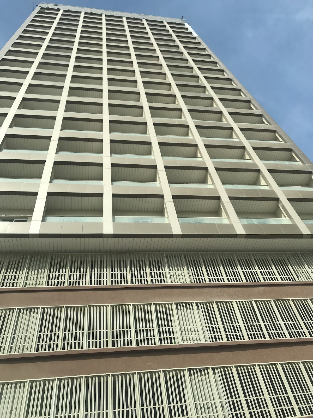 Upward view of balcony grid and parking podium
