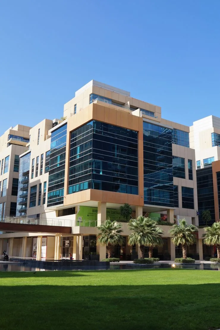Stepped beige and dark-glass building across lawn