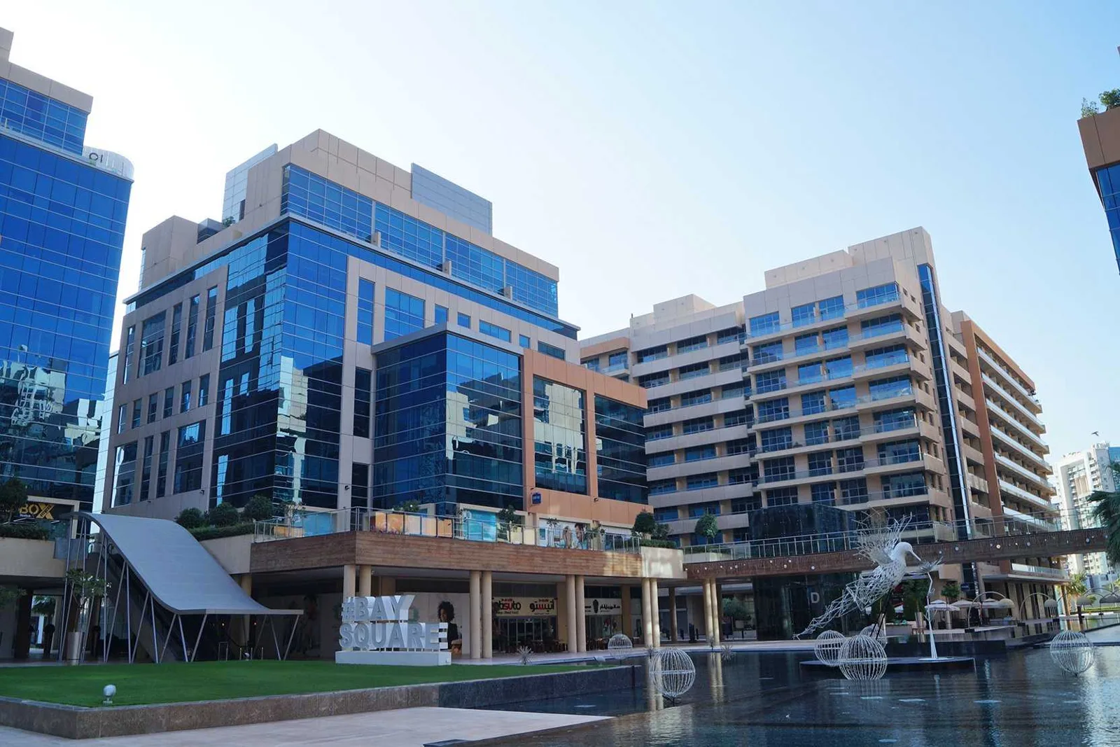 Blue-glass building beside Bay Square water feature