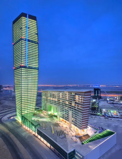 Tower lit at dusk beside podium and residential block