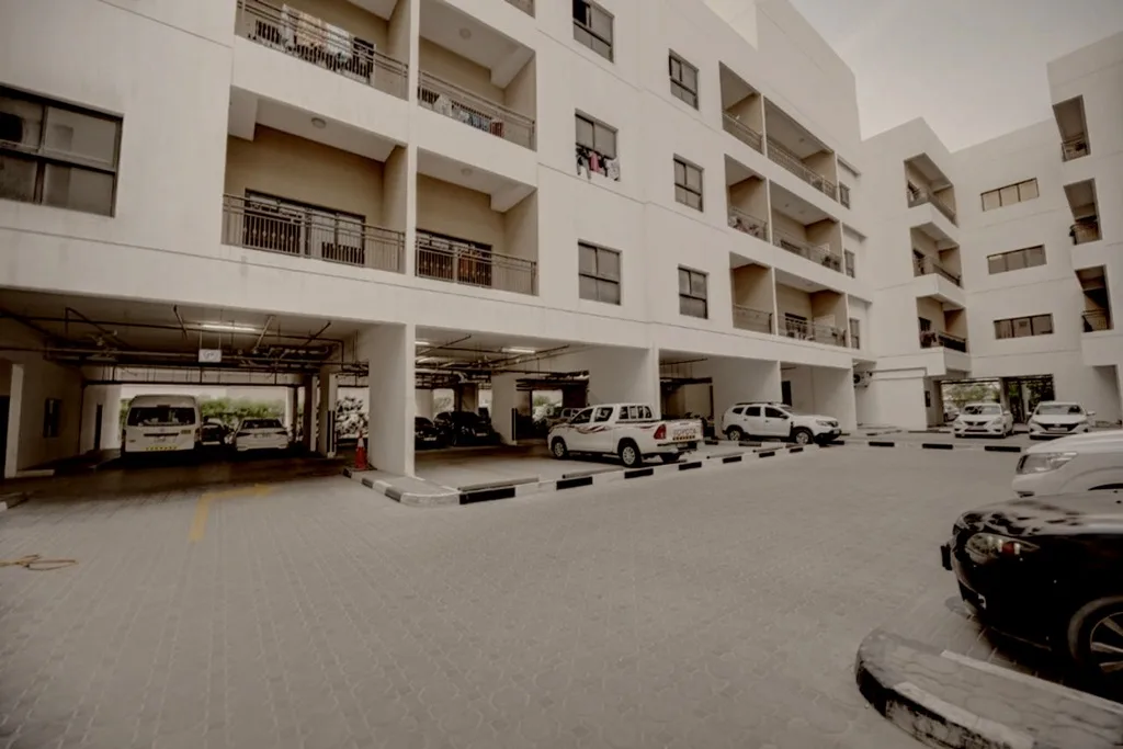 White apartment block with ground-level parking and balconies