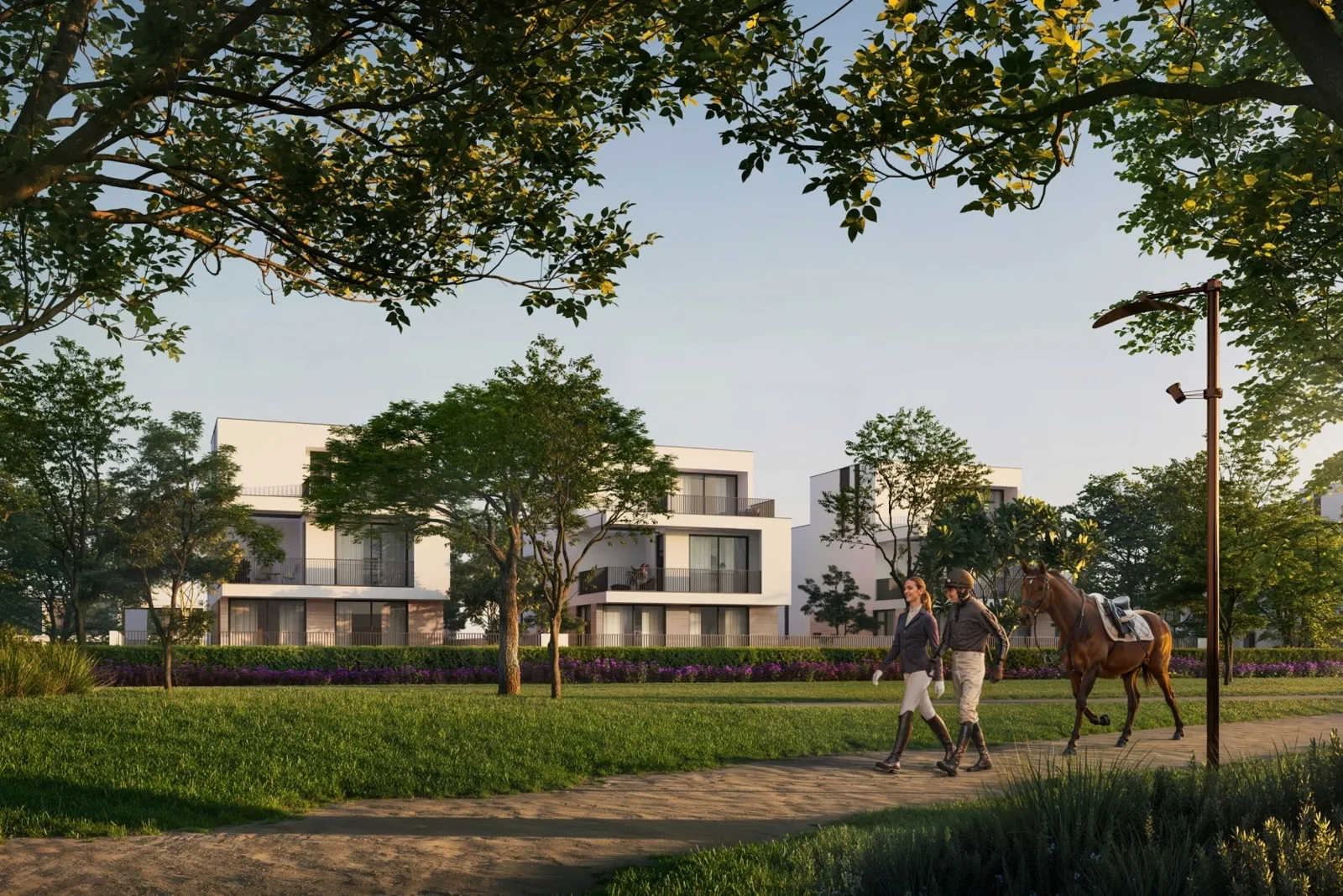 White low-rise homes across park lawn with riders