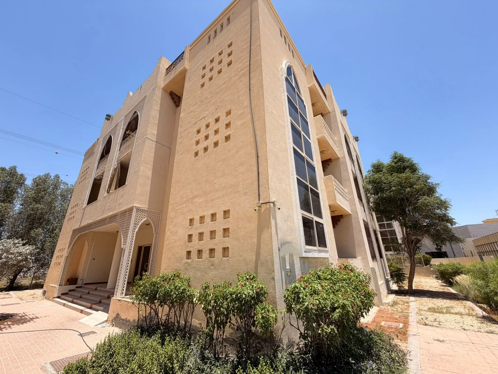 Sandstone Arabic-style low-rise with arched entrance and balconies