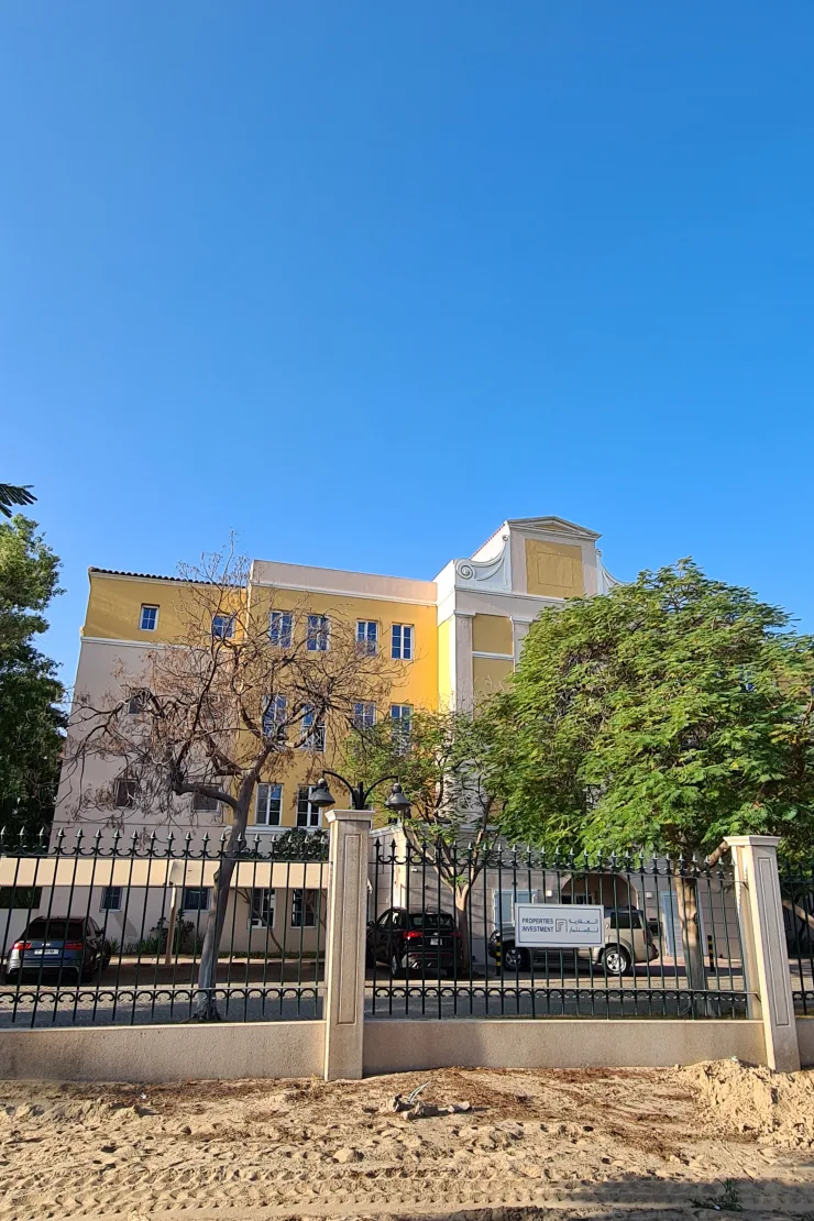 Yellow apartment block behind fence, Garden East