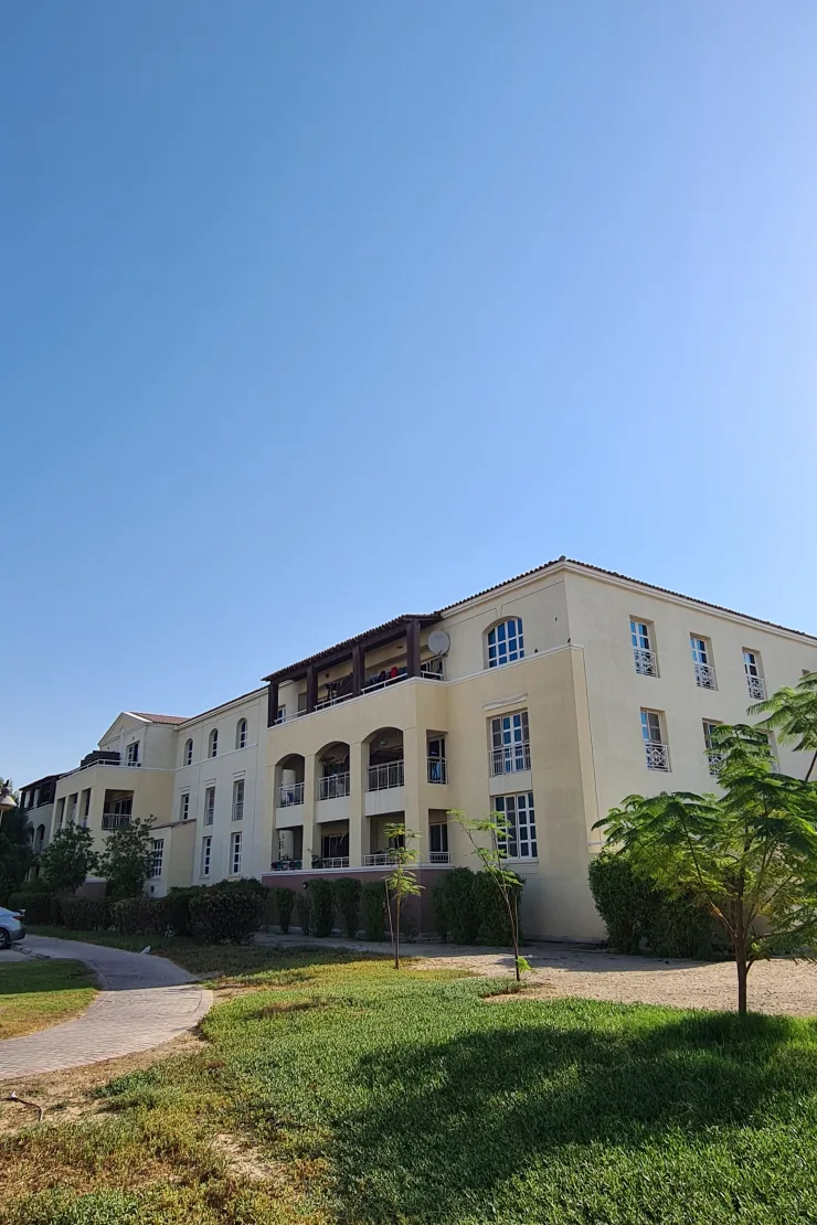 Cream three-storey block with arched balconies and lawn