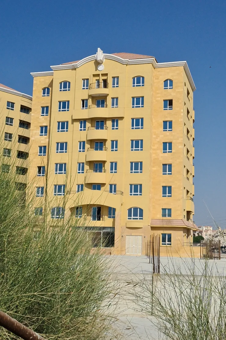 Sandy-yellow residential tower with arched windows and balconies