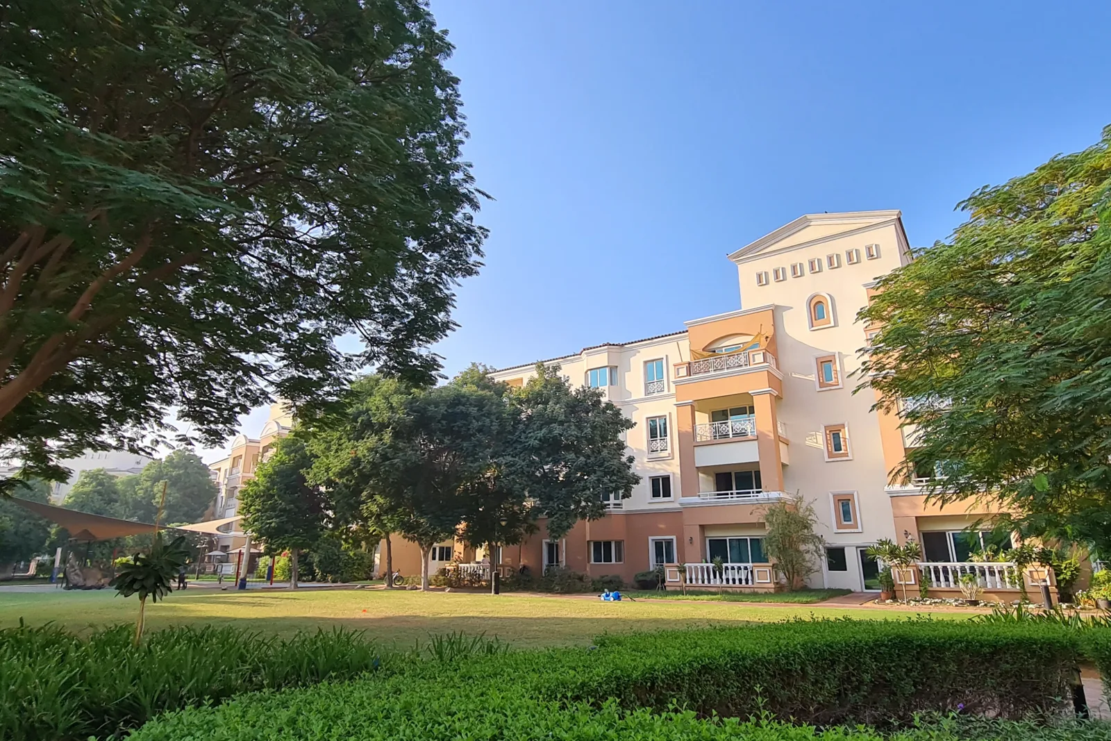 Peach Mediterranean-style apartment block seen across lawn