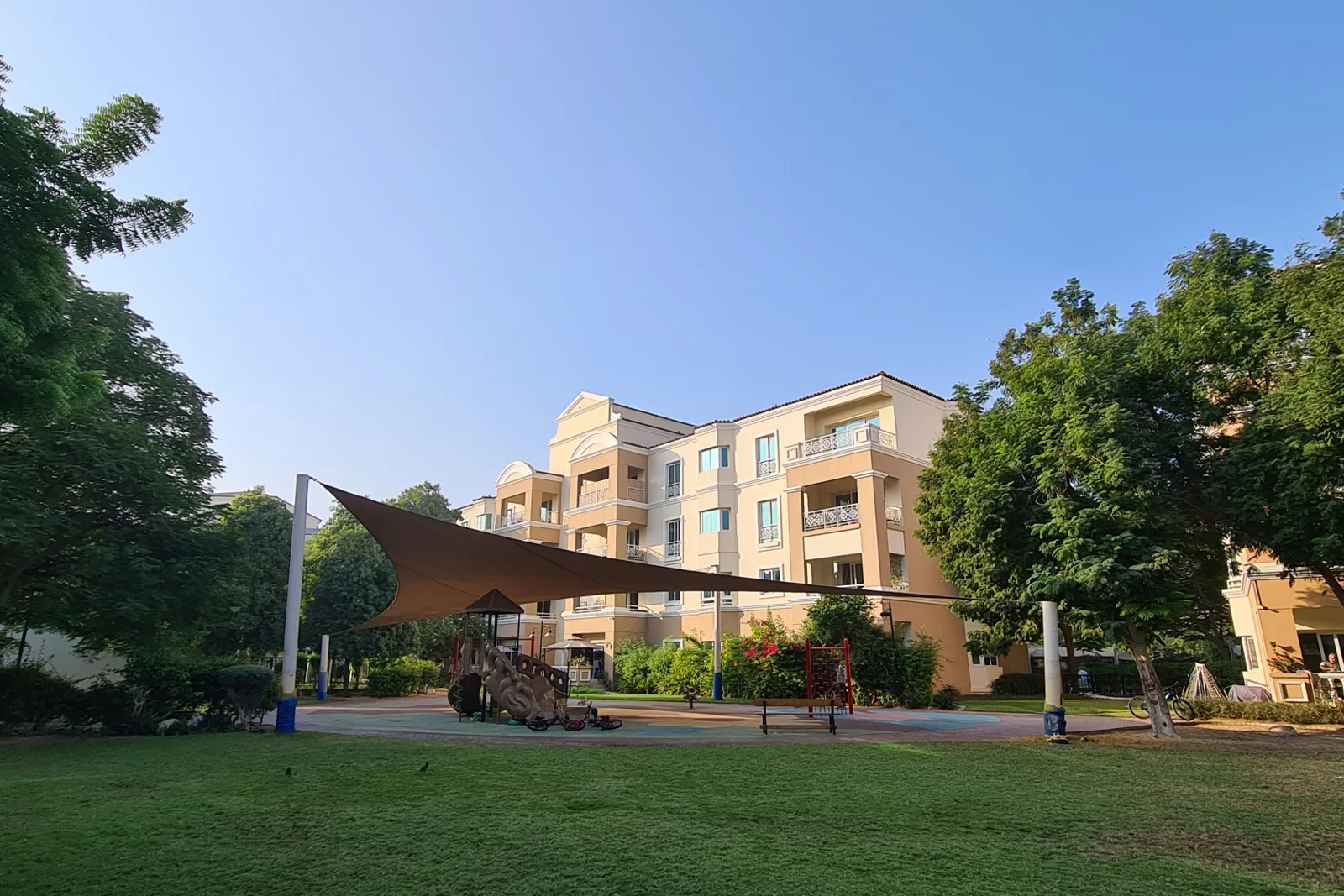 Apartment block behind playground with shade sail