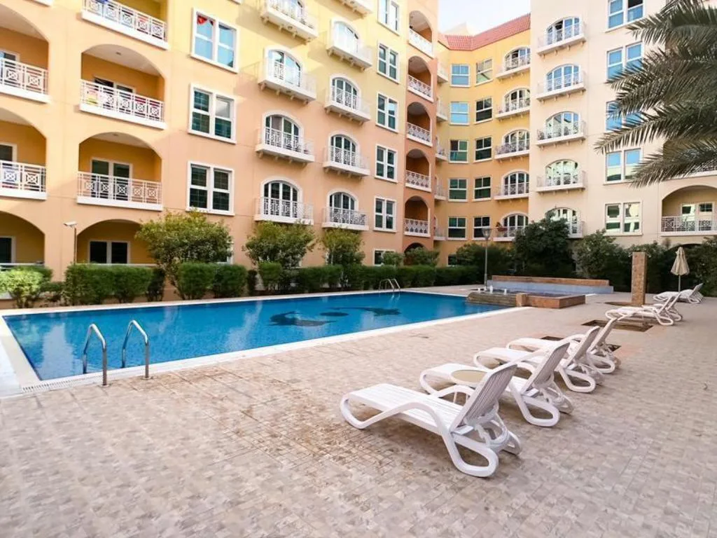 Courtyard pool with dolphin mosaic beside arched balconies
