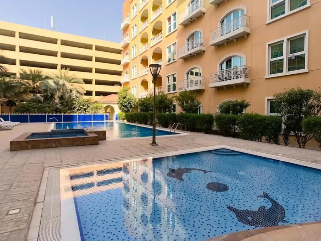 Pool and jacuzzi with dolphin mosaic below building facade
