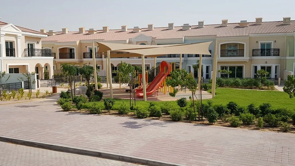 Townhouses behind a shaded playground and lawn
