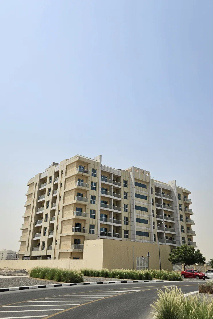 Mid-rise beige residential block with balconies, seen from the street