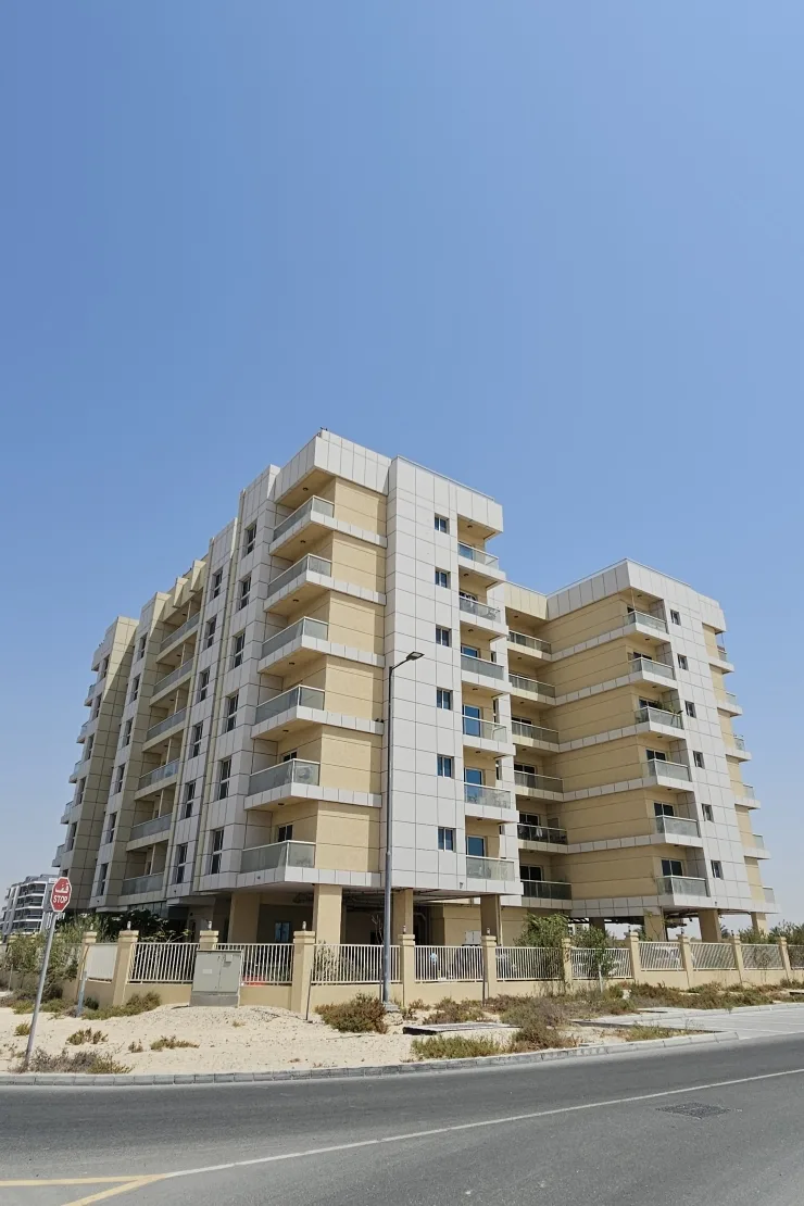 Full exterior of beige mid-rise with balconies