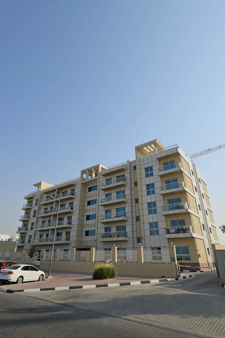 Completed beige mid-rise with glass balconies, street view