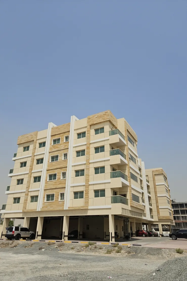 Cream and sandstone low-rise with glass balconies, podium parking