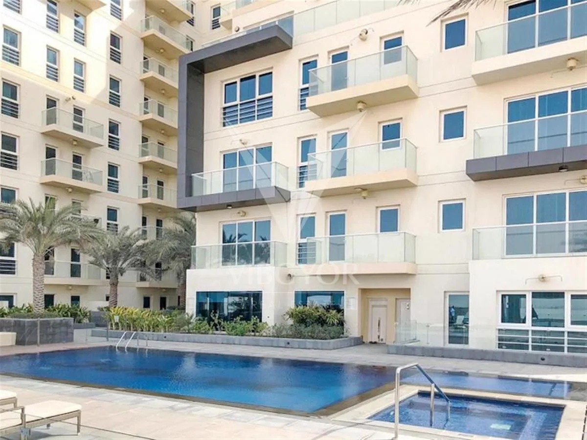 Podium pool and jacuzzi beside cream facade