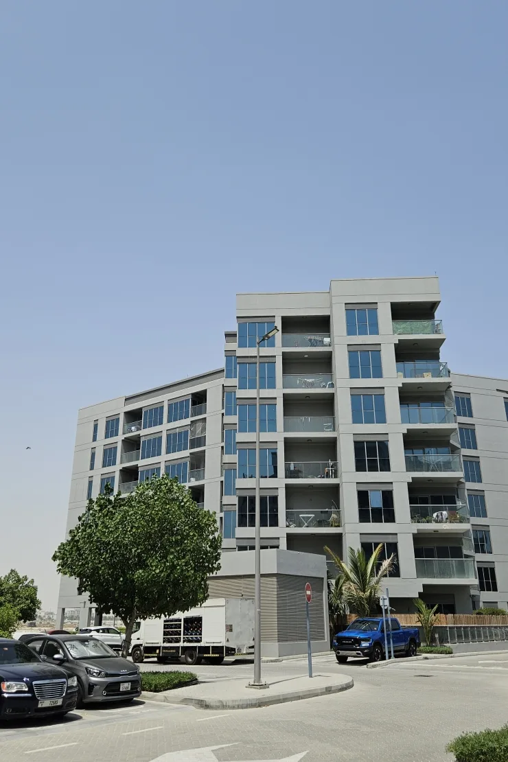 Grey mid-rise with balconies, seen from car park
