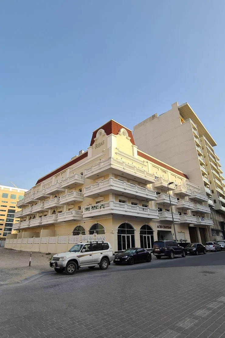 Completed ACES Chateau corner facade with balconies and red roof