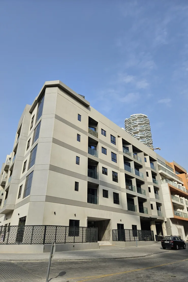 Corner view of beige building with black fence