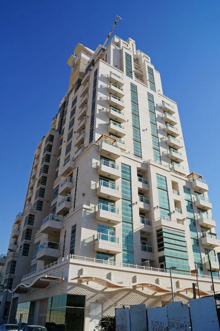 Tower facade, balconies and wavy podium canopy from street