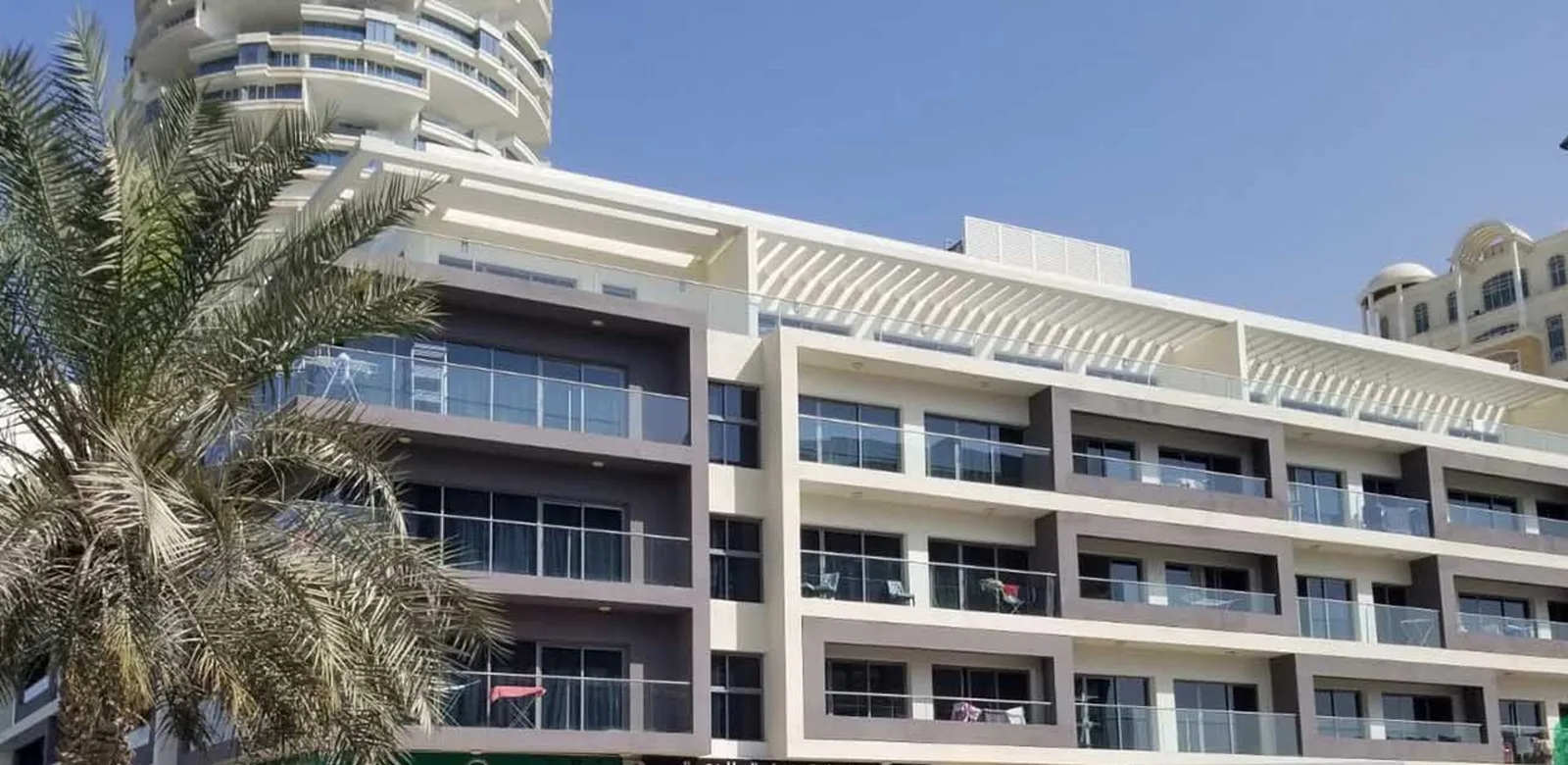 Mid-rise facade with balconies and rooftop pergola