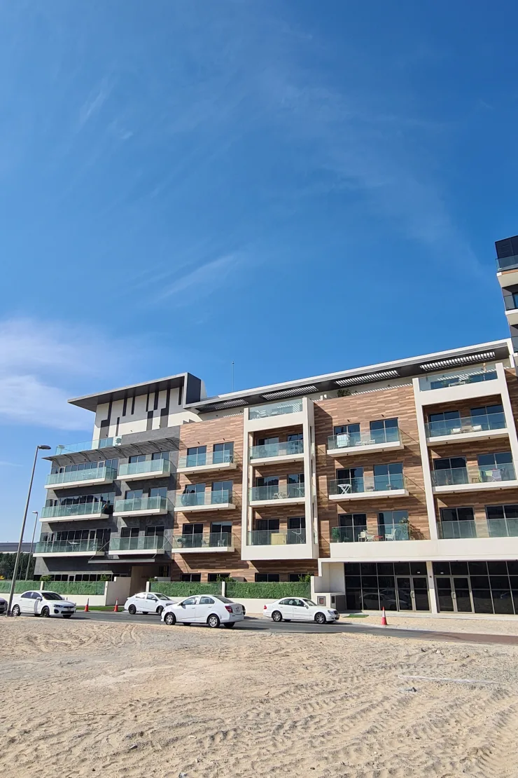 Completed low-rise facade with wood cladding and glass balconies