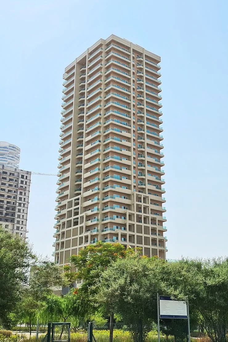 Tower with balconies seen across park greenery