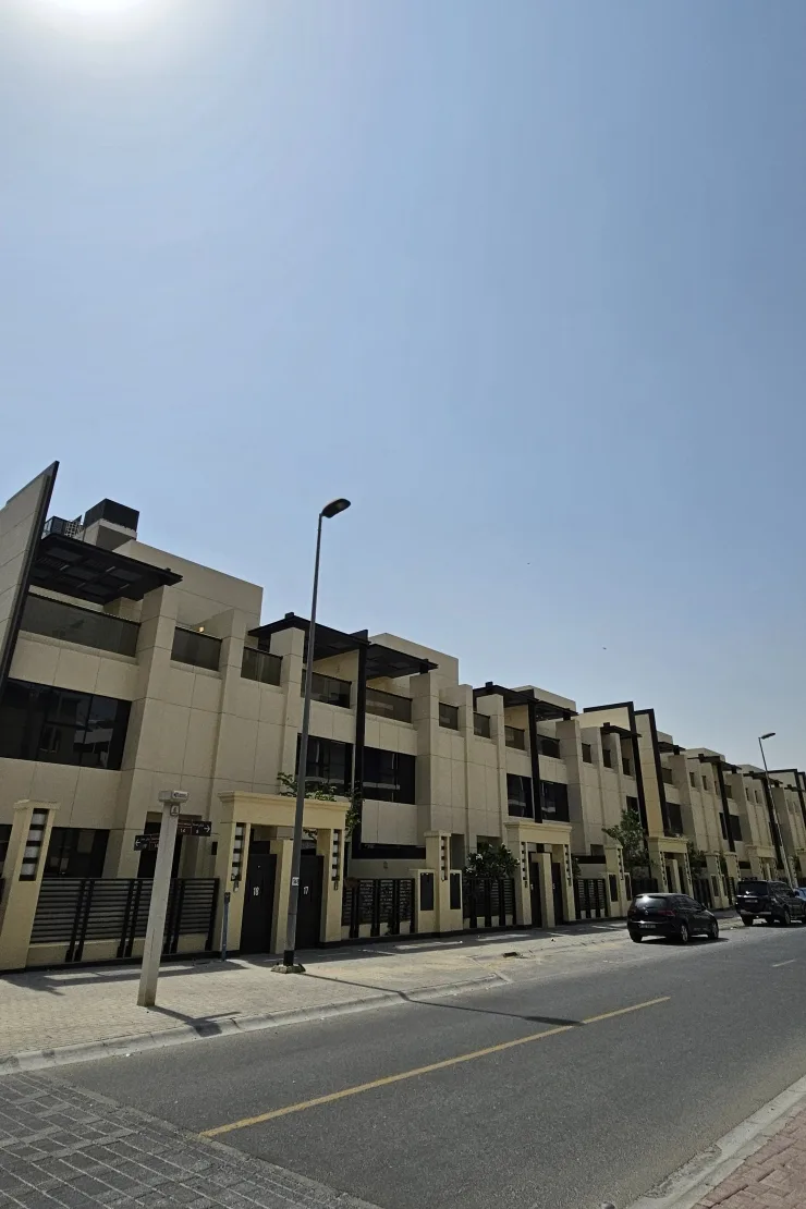 Row of cream townhouses with dark pergolas, street view