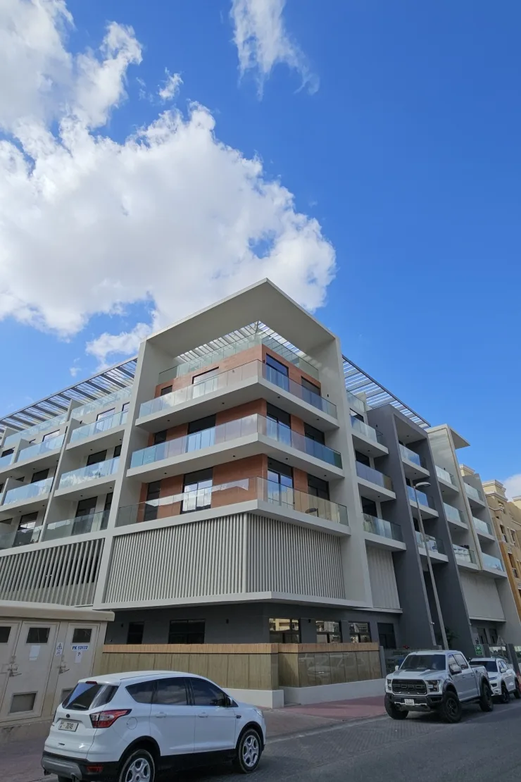 Completed corner building with glass balconies and brick-toned facade
