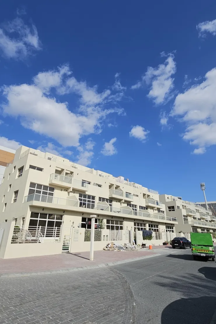 Cream terraced building with glass balconies along street