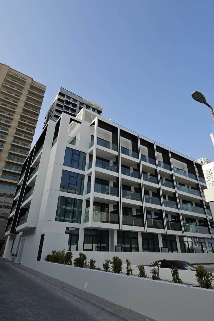 Side facade with glass balconies and landscaped base