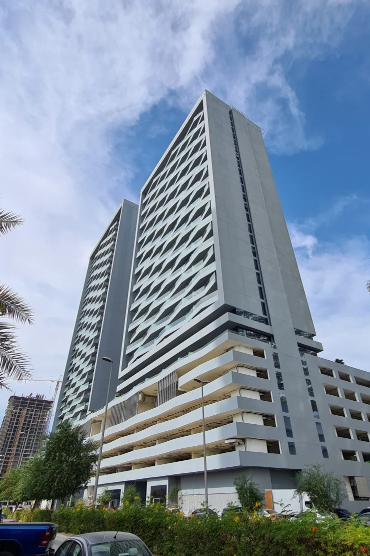 Towers and podium rising above landscaping, low angle