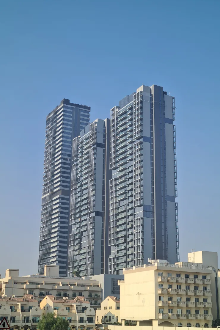 Three completed Bloom Towers rising above low-rise villas