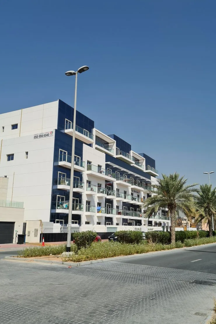 White and blue-glass mid-rise with balconies, street view
