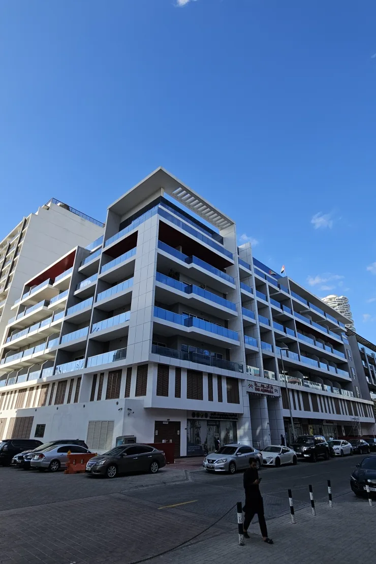 Completed corner building with blue glass balconies and rooftop pergola