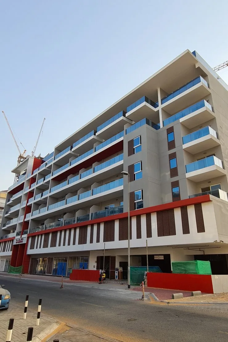 Side facade with red bands and blue balconies, finished