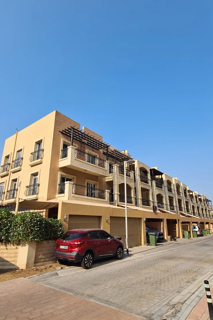 Street view of the same beige building with garages
