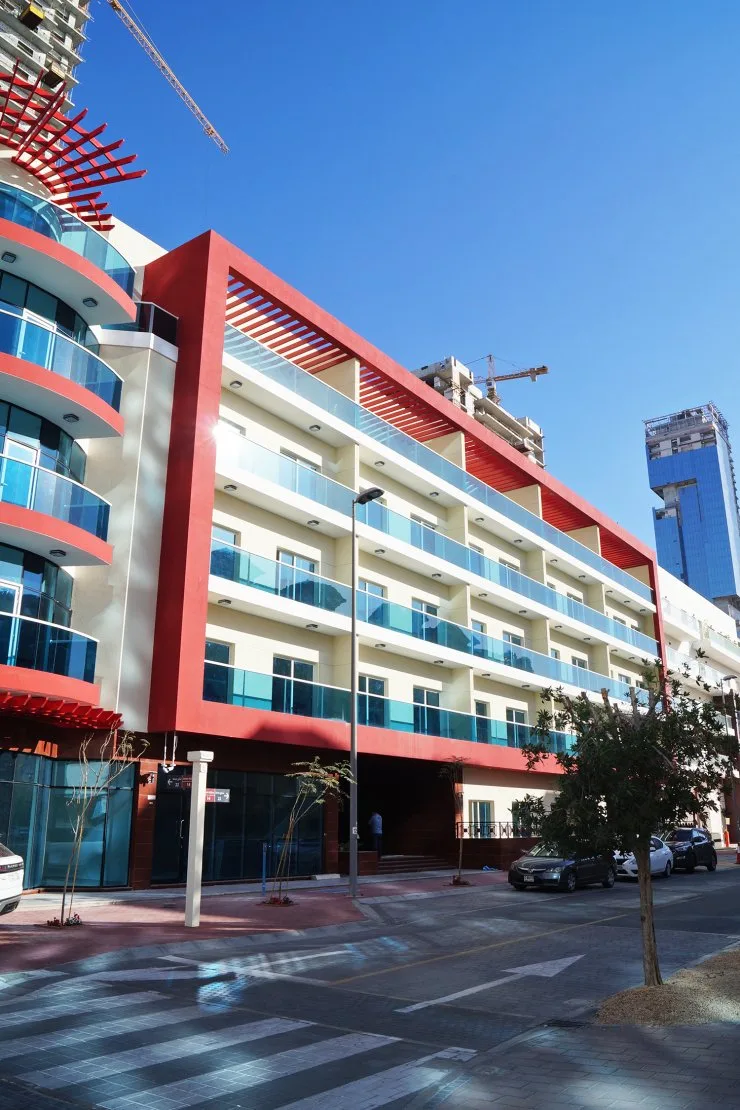 Red-framed facade with teal balconies and curved corner