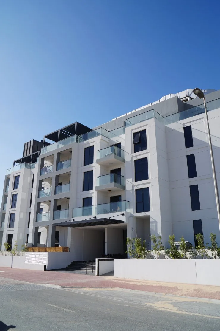 White apartment block with glass balconies, street side