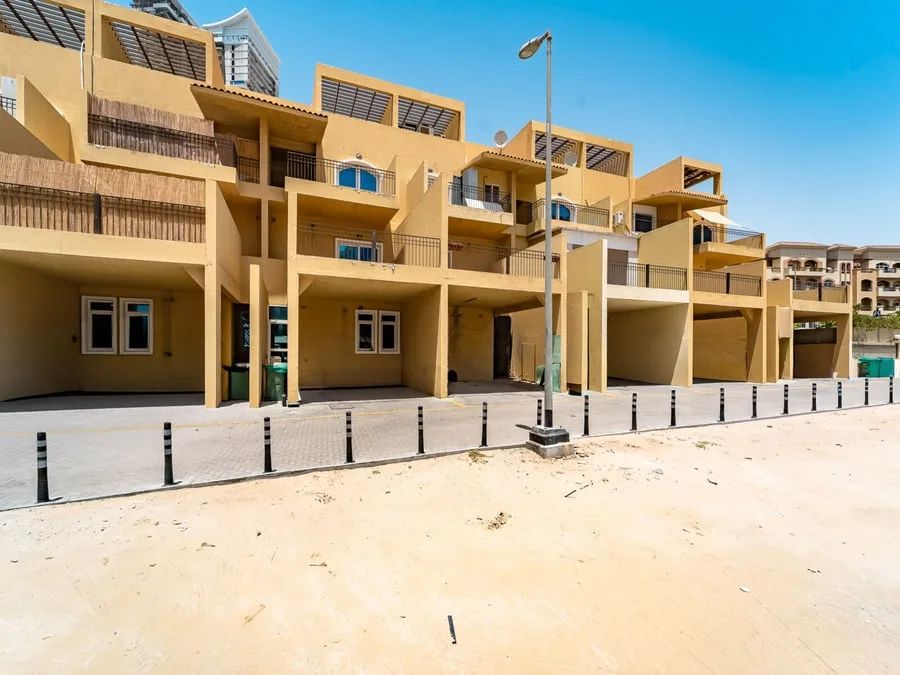 Rear of terraced sandy-yellow townhouses with carports