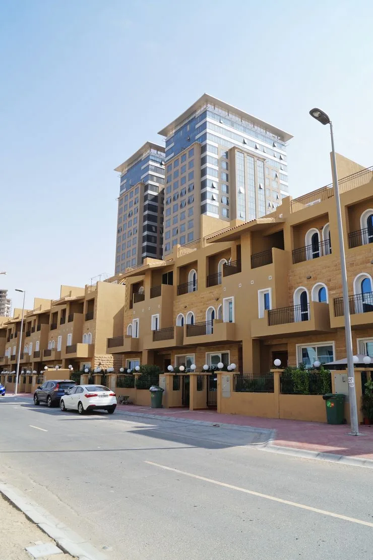 Sandstone-toned townhouse-style block with towers behind
