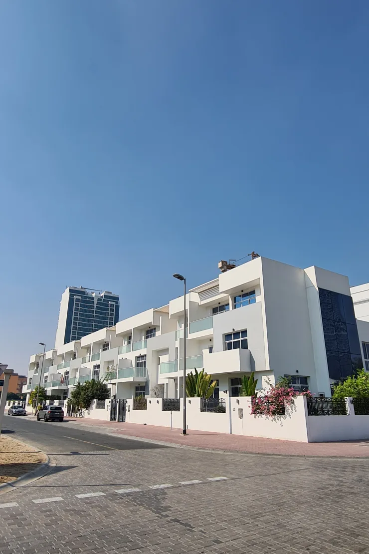 White townhouse block with glass balconies, street view