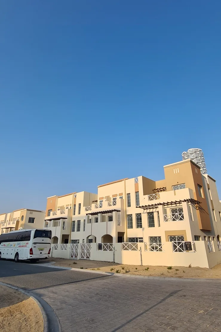 Completed cream townhouse block with balconies and fenced front