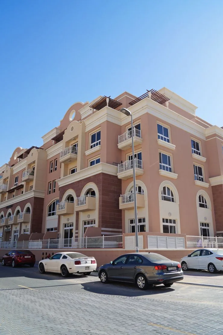 Pink and cream low-rise facade with arched windows and balconies
